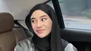 Kerudung hitam panjang model pashmina juga dikenakan olehnya. Dipadukan atasan kemeja loose silver serta rok dan tas Hermes hitam. [@clarashintareal]