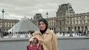 Kerudung hitam dikenakan Clara Shinta dengan dimasukan ke dalam kemeja leather coklat dipadukan rok panjang plisket dan boots hitam. Lengkap membawa tas Dior Maroon. [@clarashintareal]